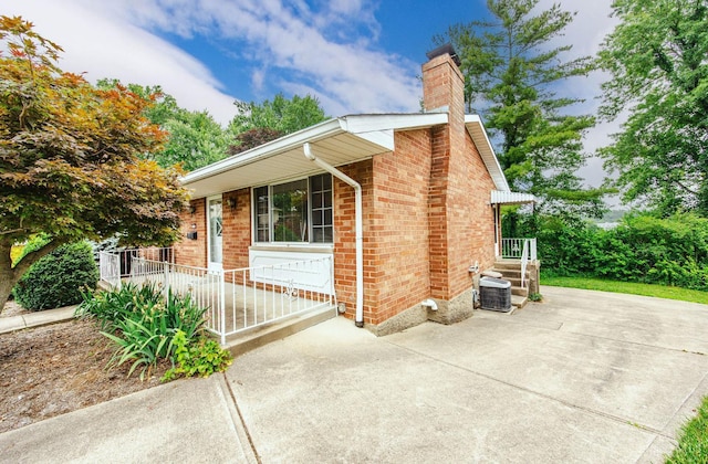 5505 Goldcrest Dr, Green Twp, OH 45238 - view of property exterior featuring a chimney, brick siding, and a porch