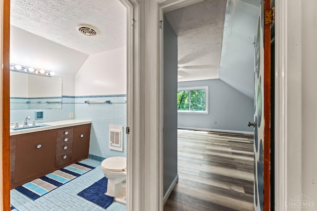 405 Hyde Park Dr, Hamilton, OH 45013 - bathroom with vanity, a textured ceiling, vaulted ceiling, tile walls, and wood finished floors