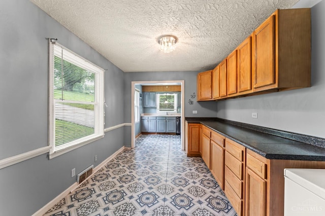 405 Hyde Park Dr, Hamilton, OH 45013 - kitchen with dark countertops, a textured ceiling, and brown cabinets