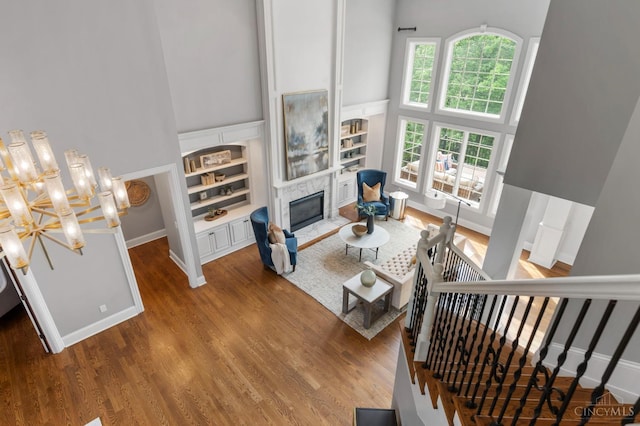 9317 E Kemper Rd, Symmes Twp, OH 45140 - living area featuring a towering ceiling, built in shelves, wood finished floors, a fireplace, and a chandelier