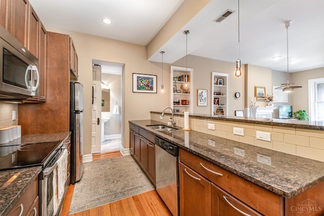 2356 Park Ave Unit 9, Cincinnati, OH 45206 - kitchen featuring stainless steel appliances, brown cabinets, light wood-style flooring, tasteful backsplash, and hanging light fixtures