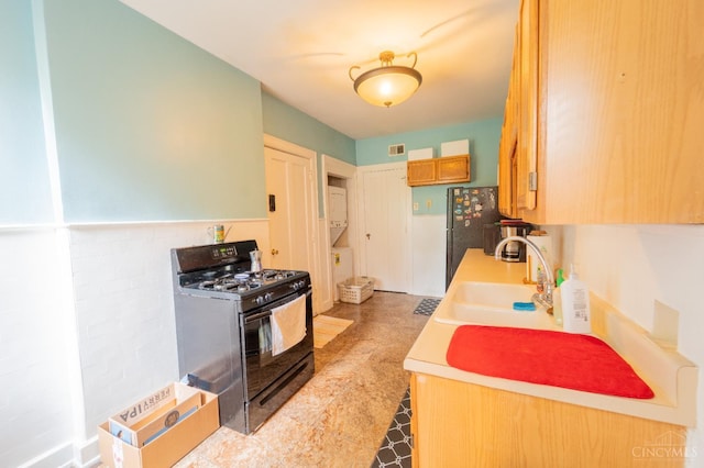 3896 Reading Rd Unit M, Cincinnati, OH 45229 - kitchen with black gas range oven, stacked washing machine and dryer, freestanding refrigerator, and light countertops