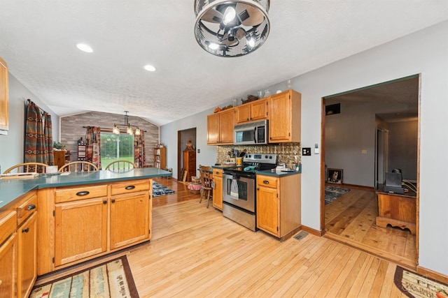 648 Odenwald Dr, Perry Twp, OH 45118 - kitchen with appliances with stainless steel finishes, lofted ceiling, light wood finished floors, tasteful backsplash, and dark countertops