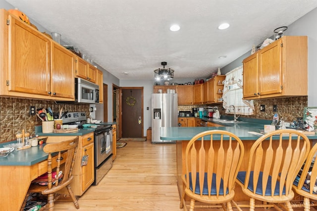 648 Odenwald Dr, Perry Twp, OH 45118 - kitchen with stainless steel appliances, light wood-style floors, decorative backsplash, a peninsula, and recessed lighting