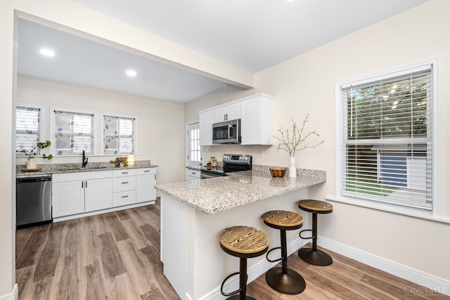 6213 Coleridge Ave, Cincinnati, OH 45213 - kitchen with stainless steel appliances, light wood-type flooring, a breakfast bar, white cabinetry, and light stone countertops