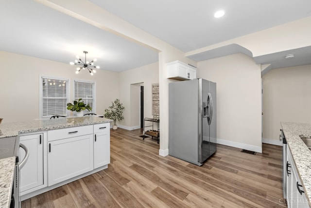 6213 Coleridge Ave, Cincinnati, OH 45213 - kitchen featuring stainless steel appliances, light wood-type flooring, a chandelier, white cabinets, and light stone countertops