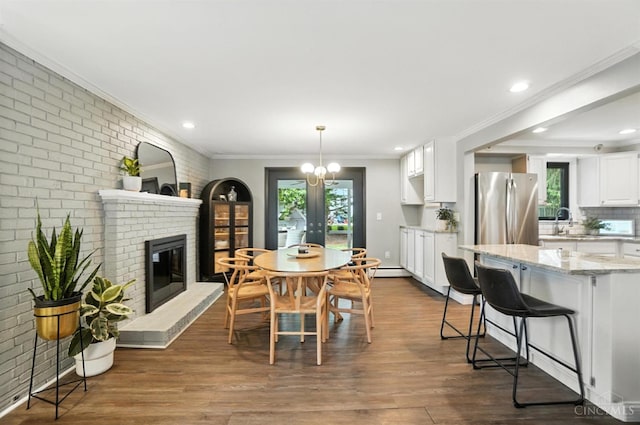 3862 Settle Rd, Mariemont, OH 45227 - dining area featuring a brick fireplace, healthy amount of natural light, french doors, dark wood finished floors, and crown molding