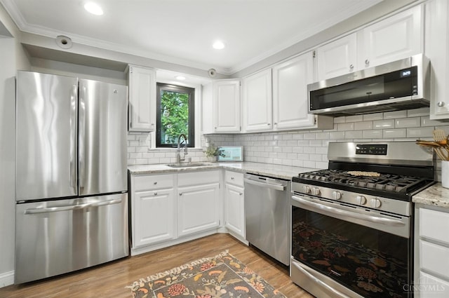 3862 Settle Rd, Mariemont, OH 45227 - kitchen featuring stainless steel appliances, crown molding, light wood finished floors, white cabinetry, and light stone countertops