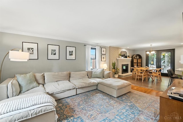 3862 Settle Rd, Mariemont, OH 45227 - living room featuring plenty of natural light, wood finished floors, crown molding, a brick fireplace, and a chandelier