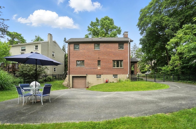 6159 Tulane Rd, Cincinnati, OH 45212 - back of house with driveway, an attached garage, a chimney, and brick siding