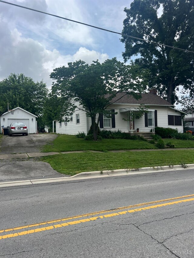 316 W S St, Hillsboro, OH 45133 - view of front of property with a detached garage, asphalt driveway, a front lawn, and an outbuilding