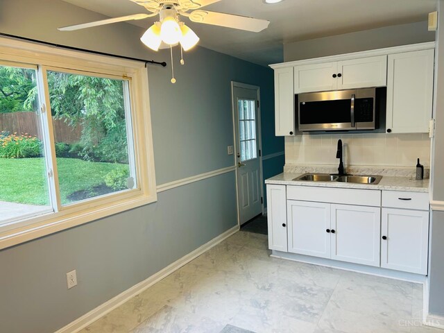 3744 Dina Ave, Cheviot, OH 45211 - kitchen featuring stainless steel microwave, ceiling fan, white cabinetry, tasteful backsplash, and light countertops