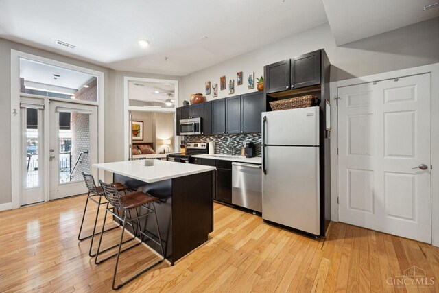 1150 Vine St Unit 15, Cincinnati, OH 45202 - kitchen with appliances with stainless steel finishes, a breakfast bar area, decorative backsplash, light countertops, and light wood-type flooring