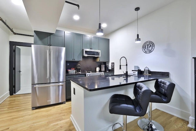 1407 Vine St Unit 203, Cincinnati, OH 45202 - kitchen with appliances with stainless steel finishes, dark countertops, a peninsula, light wood-type flooring, and a breakfast bar