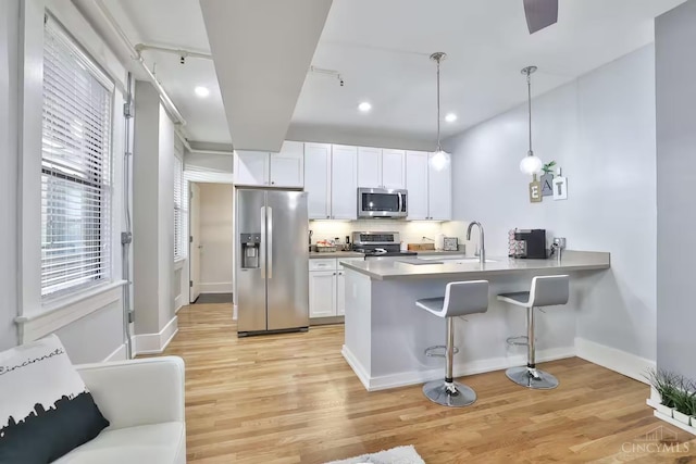 1407 Vine St Unit 303, Cincinnati, OH 45202 - kitchen with appliances with stainless steel finishes, a kitchen breakfast bar, light wood-type flooring, a peninsula, and white cabinetry