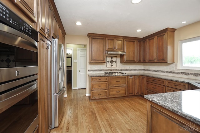3779 Windyhollow Way, Mason, OH 45040 - kitchen with stainless steel appliances, dark stone counters, light wood-style floors, backsplash, and brown cabinets