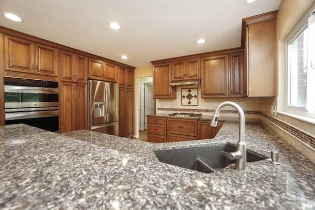 3779 Windyhollow Way, Mason, OH 45040 - kitchen featuring appliances with stainless steel finishes, backsplash, dark stone counters, recessed lighting, and brown cabinetry