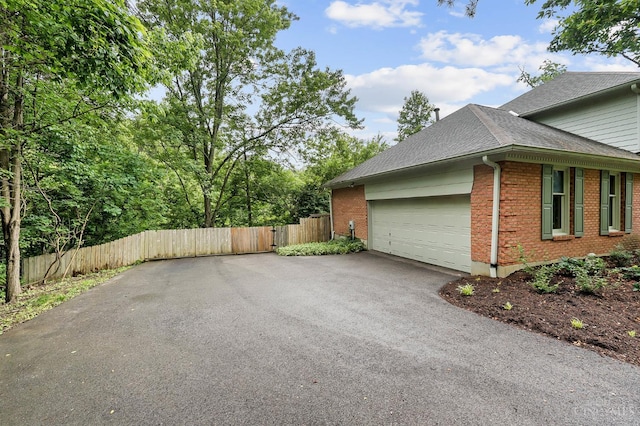 3057 Fox Den Ln, Anderson Twp, OH 45244 - view of property exterior with a shingled roof, driveway, brick siding, an attached garage, and a gate