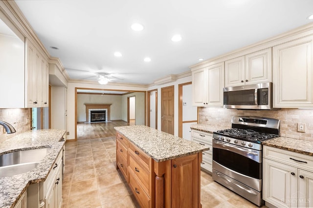 3057 Fox Den Ln, Anderson Twp, OH 45244 - kitchen featuring appliances with stainless steel finishes, ceiling fan, a glass covered fireplace, decorative backsplash, and open floor plan