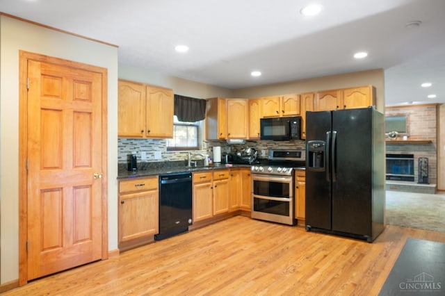 1662 W Kemper Rd, Springfield Twp, OH 45240 - kitchen with black appliances, light brown cabinets, dark countertops, light wood-style floors, and decorative backsplash