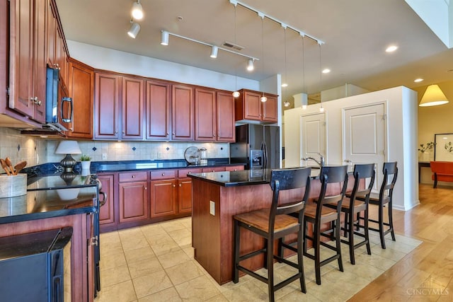 400 Pike St Unit 921, Cincinnati, OH 45202 - kitchen with black fridge, dark countertops, an island with sink, and reddish brown cabinets