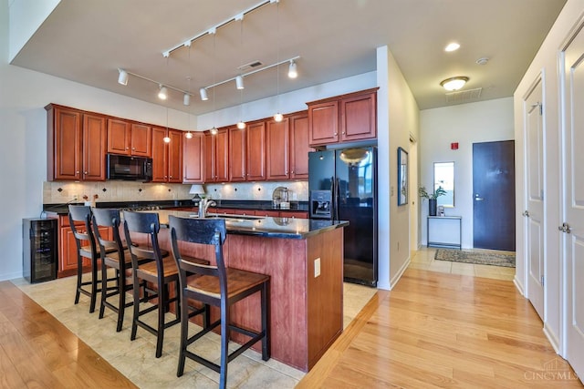 400 Pike St Unit 921, Cincinnati, OH 45202 - kitchen with black appliances, beverage cooler, dark countertops, light wood-style flooring, and an island with sink