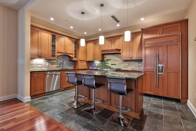 400 Pike St Unit 921, Cincinnati, OH 45202 - kitchen with stainless steel dishwasher, paneled built in refrigerator, a center island, a breakfast bar, and brown cabinetry