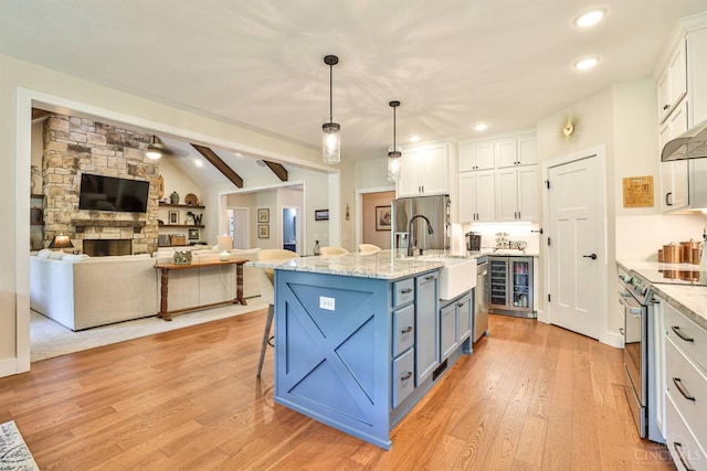 1439 Legacy Ct, Troy, OH 45373 - kitchen featuring electric range, white cabinetry, light wood-style floors, a breakfast bar area, and open floor plan