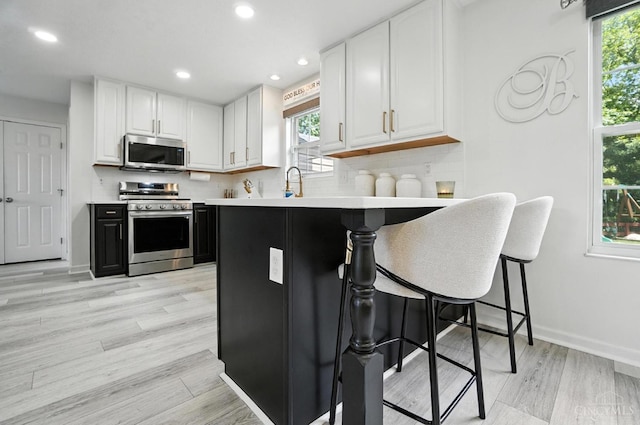4870 Highland Oaks Dr, Green Twp, OH 45248 - kitchen featuring stainless steel appliances, white cabinets, a breakfast bar area, light countertops, and recessed lighting