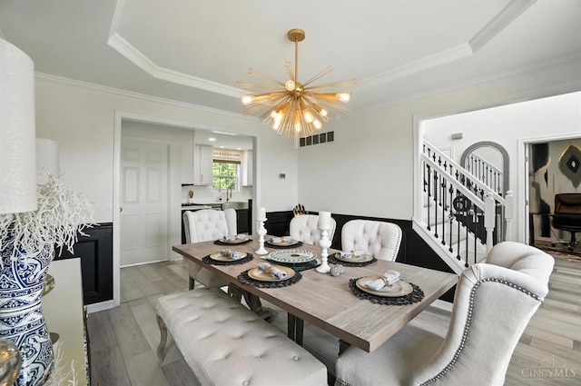 4870 Highland Oaks Dr, Green Twp, OH 45248 - dining space featuring a chandelier, stairway, light wood-type flooring, a raised ceiling, and ornamental molding