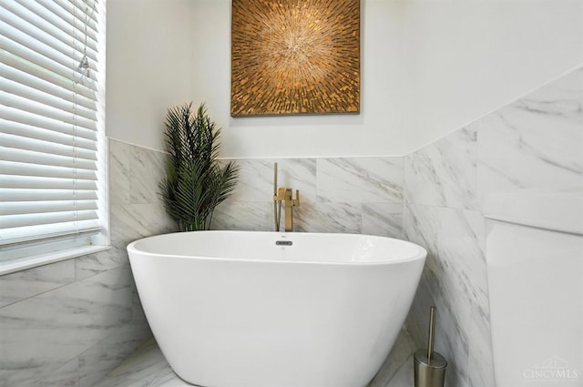 4870 Highland Oaks Dr, Green Twp, OH 45248 - full bathroom featuring marble look tiles, tile walls, a freestanding bath, and wainscoting