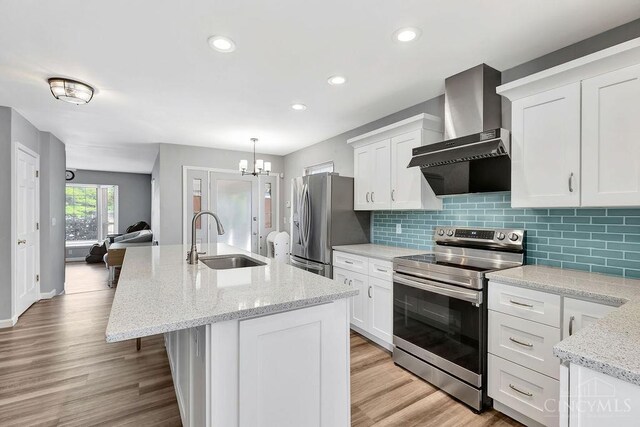 711 Van Roberts Pl, Wyoming, OH 45215 - kitchen with wall chimney exhaust hood, appliances with stainless steel finishes, an island with sink, white cabinets, and recessed lighting