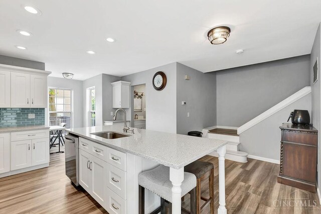 711 Van Roberts Pl, Wyoming, OH 45215 - kitchen with stainless steel dishwasher, a kitchen breakfast bar, recessed lighting, white cabinets, and light wood finished floors