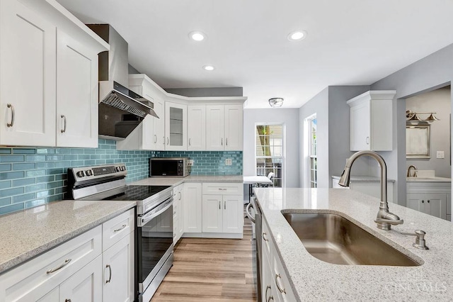 711 Van Roberts Pl, Wyoming, OH 45215 - kitchen with stainless steel appliances, wall chimney range hood, white cabinets, light stone countertops, and recessed lighting