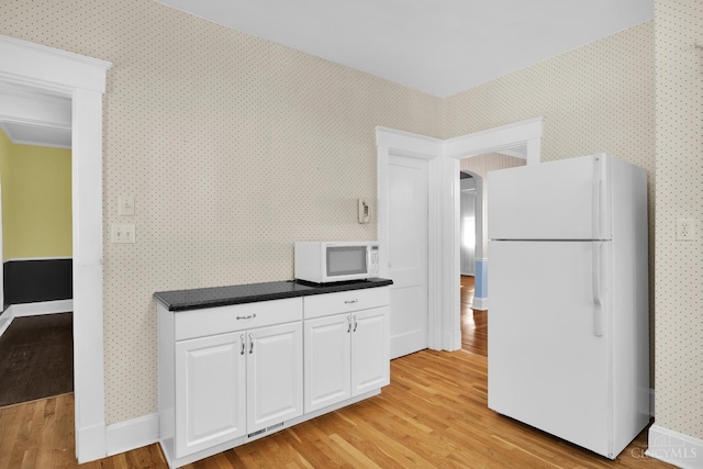 3459 Alta Vista Ave, Cheviot, OH 45211 - kitchen featuring white appliances, light wood-type flooring, white cabinets, wallpapered walls, and dark countertops