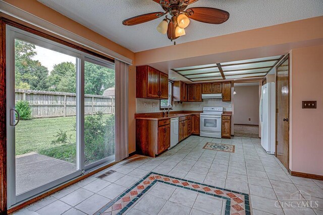 2974 Acer Ct, Ross Twp, OH 45013 - kitchen featuring white appliances, under cabinet range hood, healthy amount of natural light, light tile patterned floors, and a textured ceiling