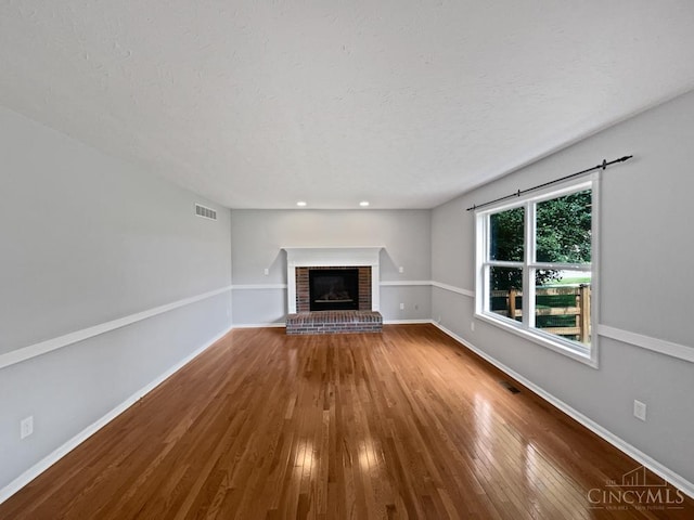 6336 Lansing Ct, Liberty Twp, OH 45011 - unfurnished living room featuring a brick fireplace, wood finished floors, recessed lighting, and a textured ceiling