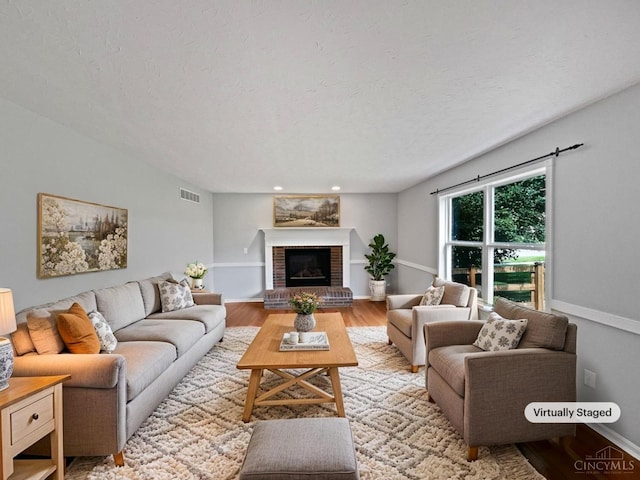 6336 Lansing Ct, Liberty Twp, OH 45011 - living room with a brick fireplace, light wood-style floors, a textured ceiling, and recessed lighting