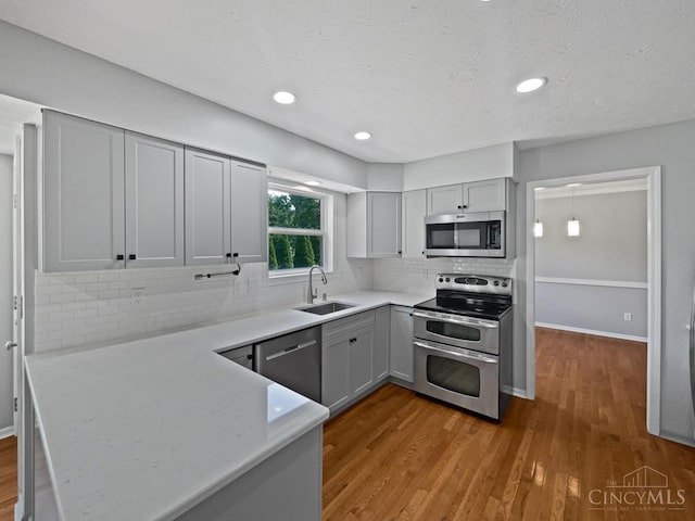 6336 Lansing Ct, Liberty Twp, OH 45011 - kitchen featuring stainless steel appliances, gray cabinetry, wood finished floors, decorative backsplash, and a peninsula