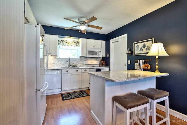 8050 Redhaven Ct, Colerain Twp, OH 45247 - kitchen featuring white appliances, a breakfast bar area, white cabinetry, ceiling fan, and light wood-style floors