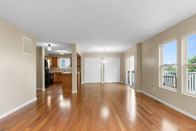 216 Lights Pointe Ct, New Richmond, OH 45157 - unfurnished living room with healthy amount of natural light, wood finished floors, and a chandelier