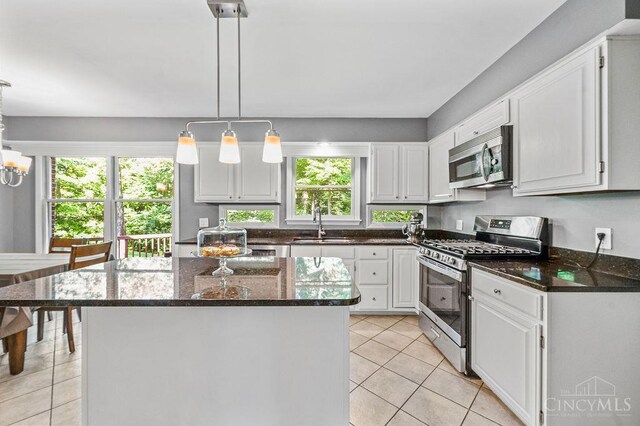 7029 Stonington Rd, Anderson Twp, OH 45230 - kitchen featuring appliances with stainless steel finishes, light tile patterned floors, white cabinets, dark stone counters, and a kitchen island