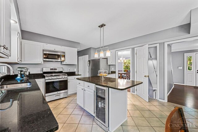 7029 Stonington Rd, Anderson Twp, OH 45230 - kitchen featuring appliances with stainless steel finishes, wine cooler, white cabinets, light tile patterned floors, and hanging light fixtures