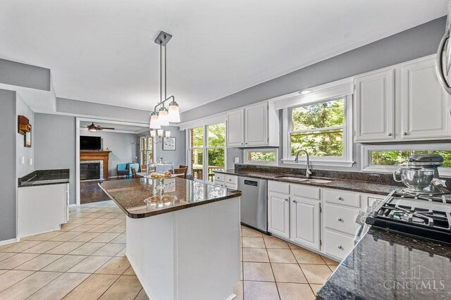 7029 Stonington Rd, Anderson Twp, OH 45230 - kitchen with dishwasher, dark stone countertops, light tile patterned floors, a center island, and white cabinetry