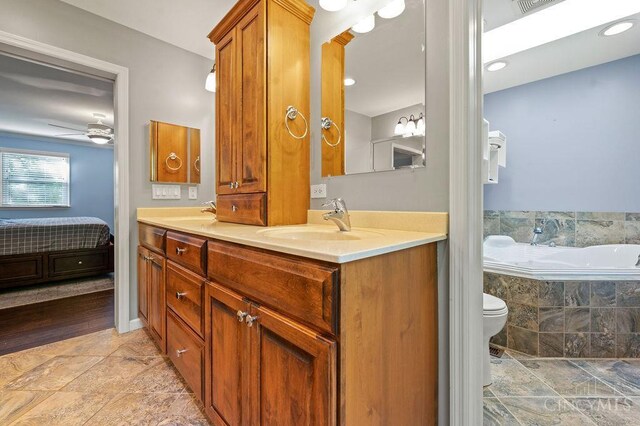 7029 Stonington Rd, Anderson Twp, OH 45230 - full bath with double vanity, a bath, connected bathroom, a ceiling fan, and stone finish floors