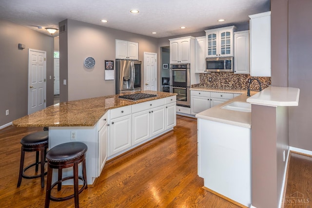 3773 Top Flite Ln, Mason, OH 45040 - kitchen with appliances with stainless steel finishes, a kitchen island, wood finished floors, white cabinetry, and recessed lighting