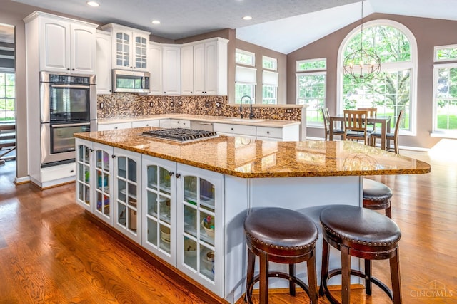 3773 Top Flite Ln, Mason, OH 45040 - kitchen featuring stainless steel appliances, glass insert cabinets, dark wood finished floors, white cabinetry, and vaulted ceiling