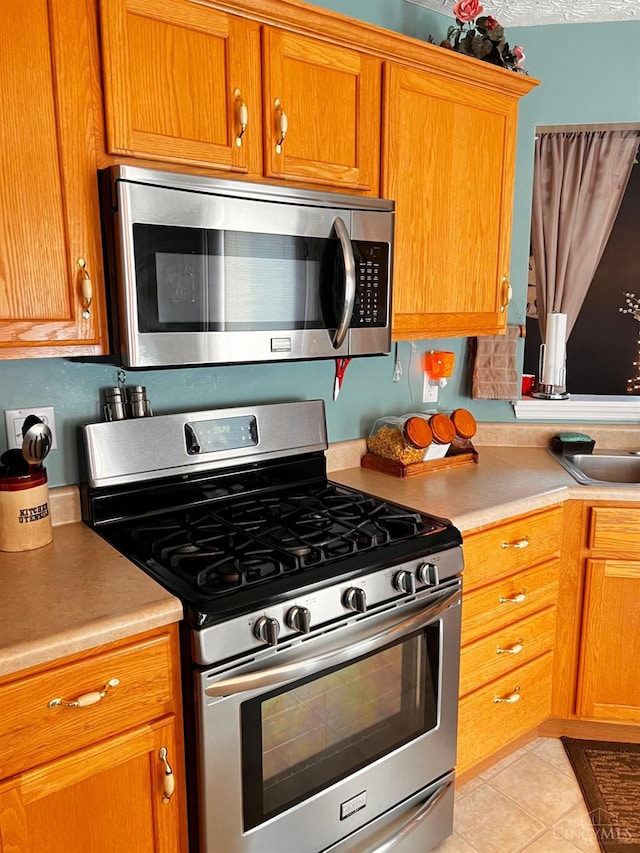 420 Lake Shore Dr, Lebanon, OH 45036 - kitchen with stainless steel appliances, light countertops, brown cabinetry, and light tile patterned flooring