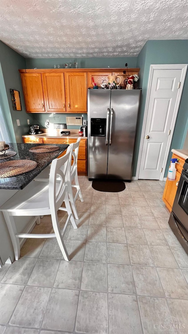 420 Lake Shore Dr, Lebanon, OH 45036 - kitchen with stainless steel fridge, brown cabinets, stove, light tile patterned floors, and a textured ceiling