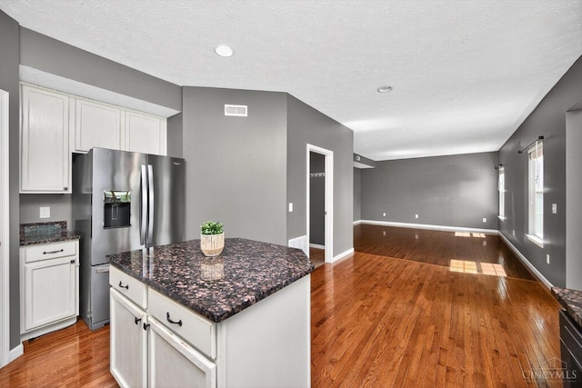 9985 Scotch Pine Dr, Clearcreek Twp, OH 45066 - kitchen featuring stainless steel fridge, open floor plan, white cabinets, wood finished floors, and dark stone counters